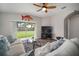 Comfortable living room featuring sliding glass doors opening to a well-maintained backyard and a ceiling fan at 17413 Garden Heath Ct, Land O Lakes, FL 34638