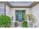 Close up of the front door with green paint, trimmed in white, and decorative posts and bushes at 18807 Tournament Trl, Tampa, FL 33647