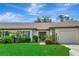 Charming single-story home with a well-manicured lawn, lush landscaping, and an attached garage at 18807 Tournament Trl, Tampa, FL 33647
