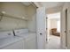 Convenient laundry room with washer and dryer hookups, a storage shelf, and seamless access to other rooms at 18807 Tournament Trl, Tampa, FL 33647