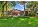 Backyard featuring a screened-in pool and patio area, with mature palm trees and lush landscaping at 1915 Floresta View Dr, Tampa, FL 33618