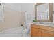 Bright bathroom with a tub, shower curtain, wooden vanity, decorative mirror, and linen closet at 1915 Floresta View Dr, Tampa, FL 33618