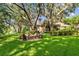 Backyard fire pit surrounded by Adirondack chairs with mature trees, luscious green grass and water in the distance at 1915 Floresta View Dr, Tampa, FL 33618