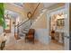 Bright foyer featuring a classic staircase, travertine tile flooring, chair rail detail, and powder room access at 1915 Floresta View Dr, Tampa, FL 33618