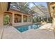 Stunning screened-in swimming pool with sun shelf, spa and adjacent covered lounge area at 1915 Floresta View Dr, Tampa, FL 33618