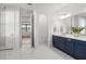 Well-lit bathroom with marble floors, blue vanity, and an open doorway to the bedroom at 2563 Ocean Breeze Ln, Clearwater, FL 33761
