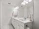 Bright bathroom featuring double sinks, white cabinets, gold hardware, and a large mirror at 2563 Ocean Breeze Ln, Clearwater, FL 33761