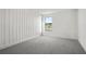 Minimalist bedroom with gray carpet, textured accent wall, and peaceful lake views from the window at 2563 Ocean Breeze Ln, Clearwater, FL 33761