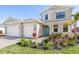 Charming two-story home featuring a welcoming blue door, two-car garage, and lush landscaping at 2563 Ocean Breeze Ln, Clearwater, FL 33761