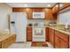Traditional kitchen with wooden cabinetry, white appliances, tile flooring, and a granite countertop at 2595 Countryside Blvd # 8205, Clearwater, FL 33761
