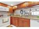 Kitchen featuring wooden cabinets, granite countertops, and a passthrough window to the living area at 2595 Countryside Blvd # 8205, Clearwater, FL 33761