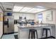 Well lit kitchen with a breakfast bar, granite countertop and stainless steel refrigerator at 2595 Countryside Blvd # 8205, Clearwater, FL 33761