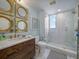 Elegant bathroom with marble walk-in shower, wooden vanity, and stylish round mirrors at 331 Cleveland St # 1806, Clearwater, FL 33755