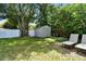 Backyard featuring a storage shed, mature trees, a white fence, and lounge chairs at 3626 17Th N St, St Petersburg, FL 33713