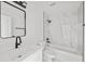 Modern bathroom with black fixtures, white marble style tile, and a combination tub and shower at 3803 E Curtis St, Tampa, FL 33610