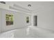 Bright bedroom featuring white walls, tray ceiling, and glossy white marble floors at 3803 E Curtis St, Tampa, FL 33610
