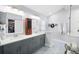 Bright bathroom with double sinks, grey cabinets, patterned floor tiles and a glass shower at 430 44Th Ne Ave, St Petersburg, FL 33703