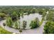 Aerial view of a tranquil pond surrounded by lush trees and a paved road, creating a scenic backdrop at 433 San Salvador Dr, Dunedin, FL 34698