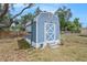 Backyard shed featuring a blue exterior, a decorative door, and adjacent greenery at 4707 Alma St, New Port Richey, FL 34652