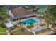 Aerial view of community pool with lounge chairs, tables, and palm trees with tennis courts nearby at 4997 Bostonian Loop, New Port Richey, FL 34655