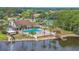 Aerial view of community clubhouse, pool, and lake surrounded by lush landscaping and mature trees at 4997 Bostonian Loop, New Port Richey, FL 34655