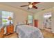 Bright bedroom features a ceiling fan, window, and adjacent bathroom entrance at 4997 Bostonian Loop, New Port Richey, FL 34655