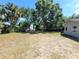 Spacious backyard featuring a mix of trees, a patch of dry grass, and a quaint, low-lying fence at 5401 E 14Th Ave, Tampa, FL 33619