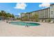 Community pool with ladder entry, lounge chairs, and nearby building at 7 Island Park Pl # 204, Dunedin, FL 34698