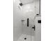 Modern glass enclosed shower with hexagon tile flooring, white marble walls and matte black fixtures at 7050 Jenner Ave, New Port Richey, FL 34655