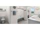 Bright bathroom featuring a shower, gray tile flooring, and double granite vanity at 718 Tidal Rock Ave, Ruskin, FL 33570