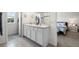 Well-lit bathroom with a double granite vanity and bedroom with a blue patterned bed at 718 Tidal Rock Ave, Ruskin, FL 33570