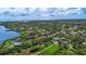 Aerial view of the houses in a lush green community that leads to a pond with ocean in the background at 7314 Hunt Club Ln, Seminole, FL 33776
