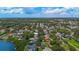 Aerial view of the houses in a lush green community that leads to a pond with ocean in the background at 7314 Hunt Club Ln, Seminole, FL 33776