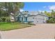 Charming two-story home showcasing a brick driveway, large shade tree, well-manicured lawn and tasteful blue accents at 7314 Hunt Club Ln, Seminole, FL 33776
