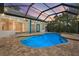 Beautiful in-ground pool and spa surrounded by brick pavers inside screened enclosure with view of lush greenery at 7314 Hunt Club Ln, Seminole, FL 33776