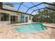 Beautiful in-ground pool and spa surrounded by brick pavers inside screened enclosure on a sunny day at 7314 Hunt Club Ln, Seminole, FL 33776