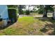 Side yard featuring a green lawn and mature trees, complemented by lush hedges and a glimpse of the street at 7336 20Th N St, St Petersburg, FL 33702
