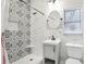 Modern bathroom featuring a patterned tile shower with a built-in niche, contemporary vanity and a round mirror at 757 32Nd N Ave, St Petersburg, FL 33704