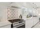 Bright kitchen featuring stainless steel stove, modern hood, and decorative backsplash and white cabinets at 757 32Nd N Ave, St Petersburg, FL 33704