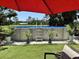 Inviting above-ground pool surrounded by lush greenery and a comfortable seating area under a red umbrella at 836 Magellan Dr, Sarasota, FL 34243