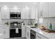Bright kitchen features white cabinets, stainless steel appliances, quartz countertops, and stylish fixtures at 9218 Glen Moor Ln, Port Richey, FL 34668