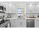 Well-lit kitchen featuring white cabinetry, stainless steel appliances and a window over the sink area at 9218 Glen Moor Ln, Port Richey, FL 34668