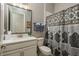 Well-lit bathroom with a large mirror, vanity with white countertop, and shower with patterned curtain at 10982 Banyan Breeze Blvd, Land O Lakes, FL 34638