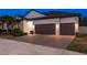 The home features a two-car garage, decorative exterior lighting, tropical landscaping, and a brick driveway at 10982 Banyan Breeze Blvd, Land O Lakes, FL 34638