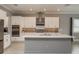 Well-lit kitchen with stainless steel appliances, white cabinetry, a stylish backsplash, and a kitchen island at 10982 Banyan Breeze Blvd, Land O Lakes, FL 34638