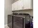 Modern laundry room features gray washer and dryer with white cabinets above for optimal storage at 10982 Banyan Breeze Blvd, Land O Lakes, FL 34638