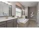 Bright bathroom with double vanity, tile flooring, large tub, and natural light at 10982 Banyan Breeze Blvd, Land O Lakes, FL 34638