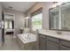 Bright bathroom with tub with tile surround, double vanity, and natural light at 10982 Banyan Breeze Blvd, Land O Lakes, FL 34638