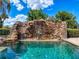 A luxurious pool featuring a stunning rock waterfall and clear, inviting water at 11715 Taylor Rd, Thonotosassa, FL 33592