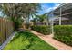 Landscaped backyard featuring a brick paver pathway, green grass, and mature trees at 11910 Keating Dr, Tampa, FL 33626
